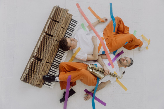 Das Musikerduo DUO STIEHLER / LUCACIU liegend mit einigen Instrumenten