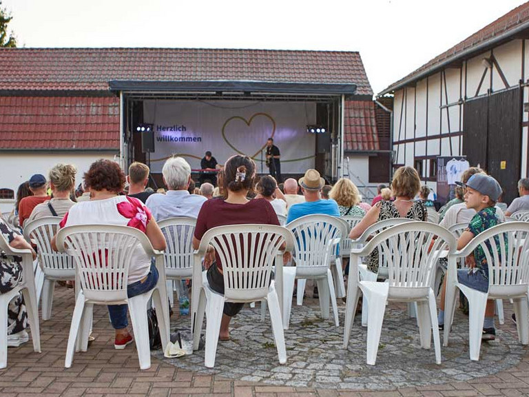 Besucher auf Stühlen mit Bühne im Hintergrund