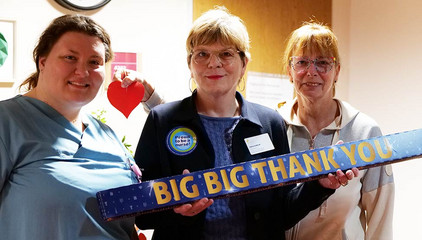 Sabine Kalkhoff, Gesamtleiterin Residenz am Wiesenkamp und Gesellschaft für Diakonie, hält mit zwei Mitarbeitenden ein Schild mit der Aufschrift "Big Big Thank You" in die Kamera am Internationalen Tag der Pflegenden in Hamburg-Volksdorf. Sabine Kalkhoff, Gesamtleiterin Residenz am Wiesenkamp und Gesellschaft für Diakonie, hält mit zwei Mitarbeitenden ein Schild mit der Aufschrift "Big Big Thank You" in die Kamera am Internationalen Tag der Pflegenden in Hamburg-Volksdorf.